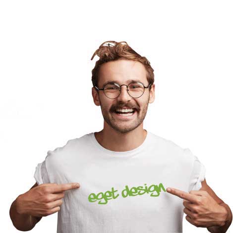 Mann med briller som peker på sin hvite t-skjorte hvor det står "eget design" med grønn tekst